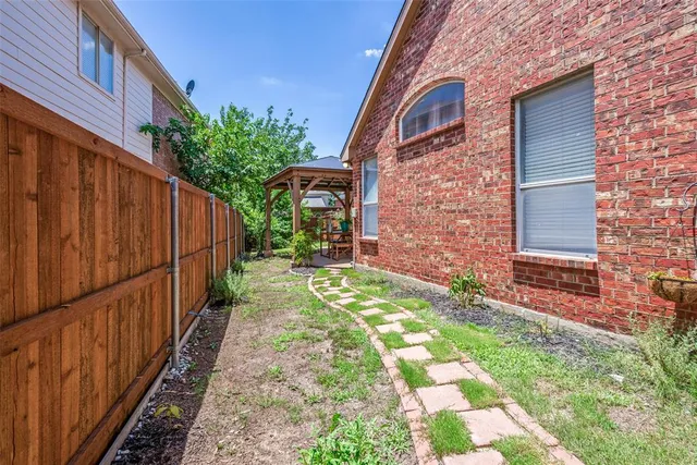 a view of a pathway of a house with backyard and wooden fence