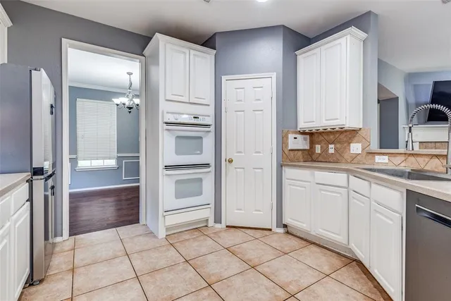 a kitchen with white cabinets and refrigerator