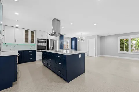 a kitchen with stainless steel appliances kitchen island granite countertop a refrigerator and a sink
