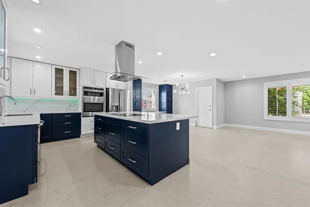 a kitchen with stainless steel appliances kitchen island granite countertop a refrigerator and a sink