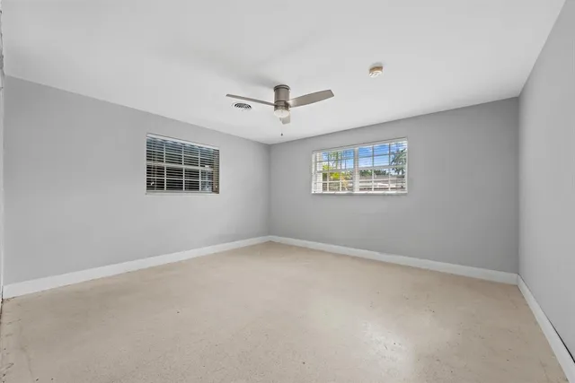 an empty room with a window and a fan