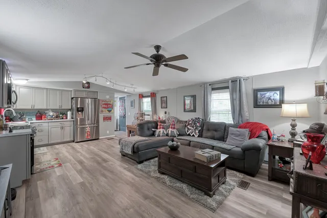 a living room with furniture kitchen view and a window