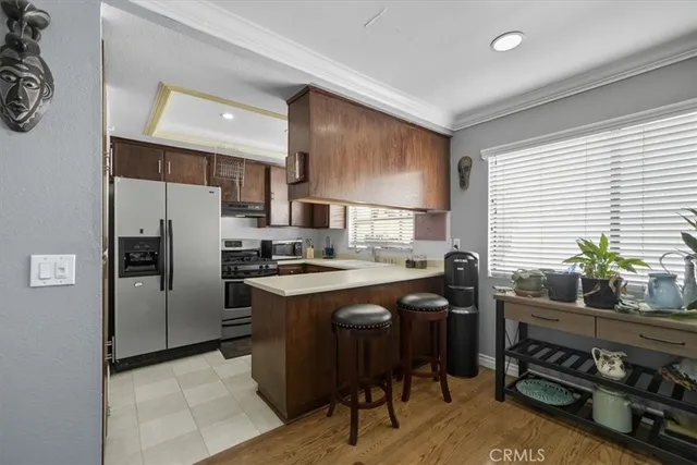 a kitchen with stainless steel appliances a stove a sink a refrigerator white cabinets and wooden floor
