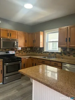 a kitchen with granite countertop a stove a sink and a microwave