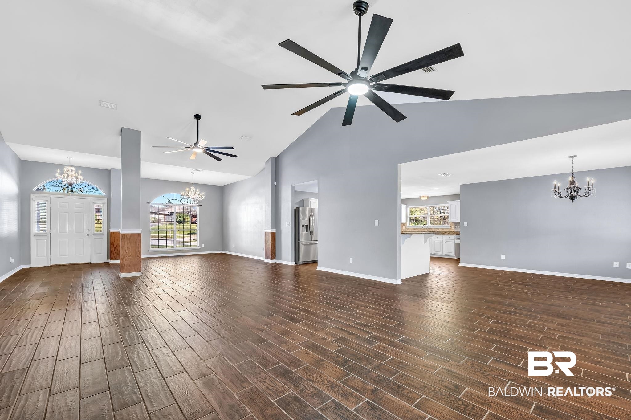 16444 Hamlet Lane Foley, AL 36535 - Photo 14 of 49 Unfurnished living room featuring high vaulted ceiling, ceiling fan with notable chandelier, baseboards, and wood tiled floor