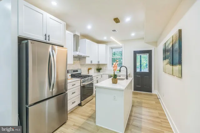 a kitchen with stainless steel appliances granite countertop a refrigerator a stove a sink dishwasher and a refrigerator with wooden floor