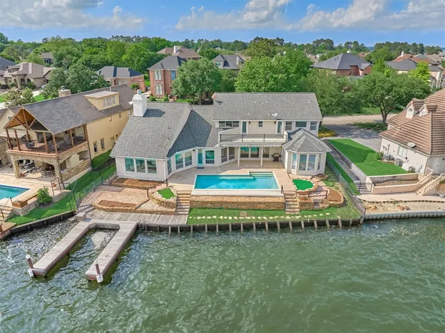 an aerial view of a house with swimming pool a yard and lake view
