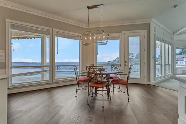 a dining room with wooden floor a chandelier a glass table and chairs