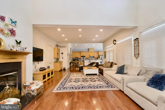 a living room with stainless steel appliances furniture wooden floor and a view of kitchen