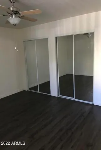 an empty room with wooden floor and a ceiling fan