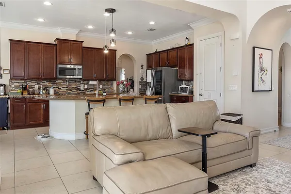 a living room with furniture kitchen view and a chandelier