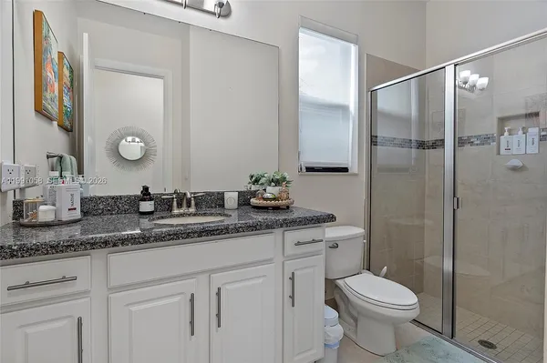 a bathroom with a granite countertop sink a toilet and a mirror