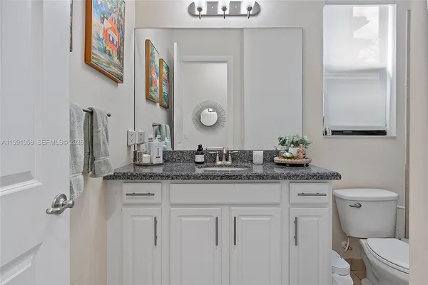 a bathroom with a granite countertop toilet sink and mirror