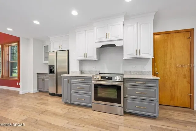 a kitchen with stainless steel appliances granite countertop a stove a refrigerator and a stove top oven