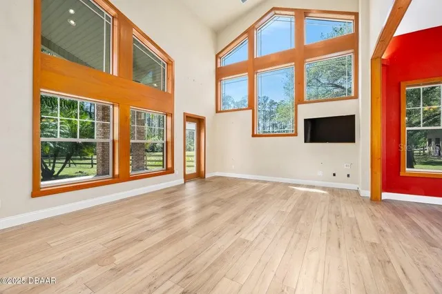 a view of an empty room with a window and wooden floor