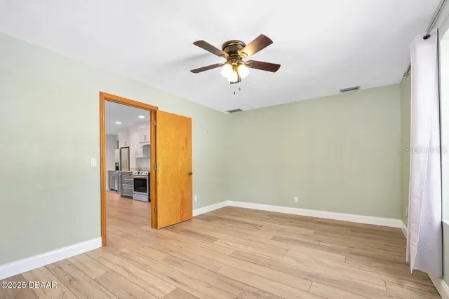 a view of empty room with wooden floor and fan