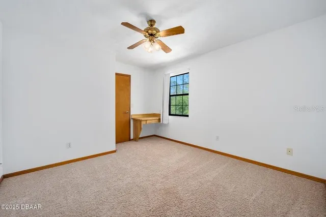 an empty room with a window and a ceiling fan