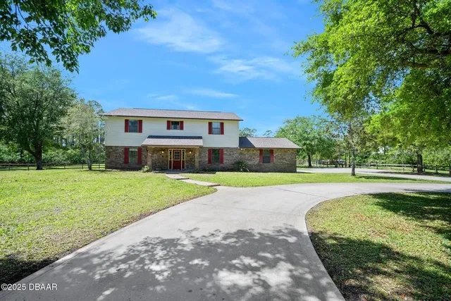 a view of a house with a big yard plants and large trees