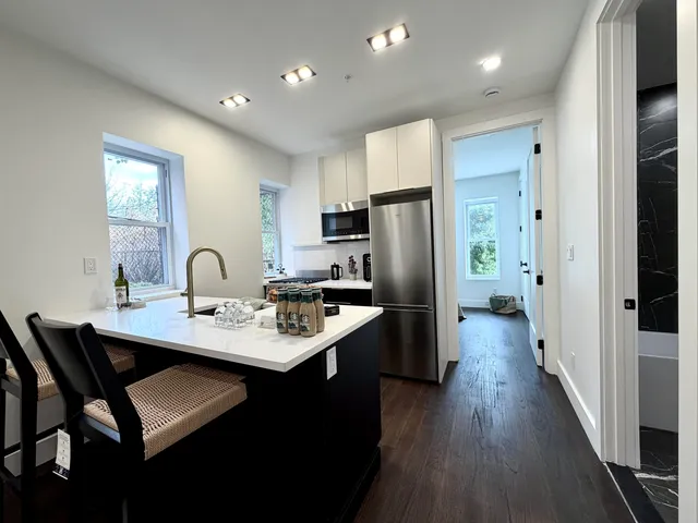 a kitchen with stainless steel appliances a refrigerator a sink a stove a table and chairs