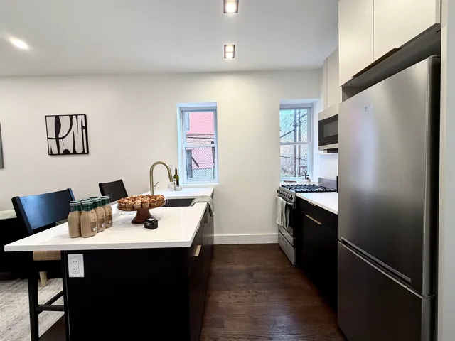 a kitchen with stainless steel appliances a sink dishwasher a refrigerator and a stove with wooden floor