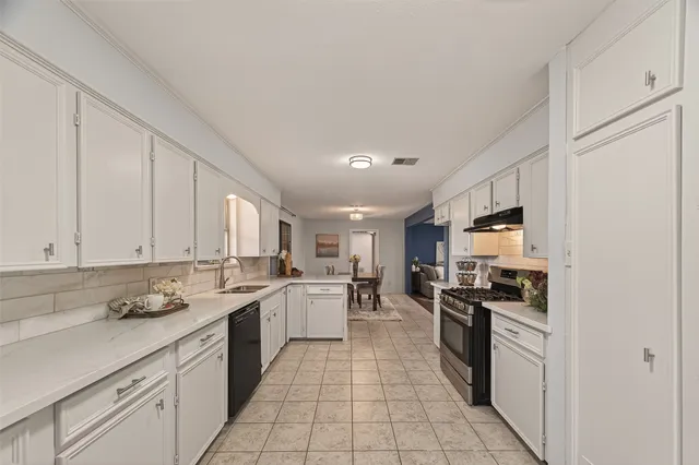 a kitchen with stainless steel appliances granite countertop a stove top oven a sink a refrigerator and white cabinets