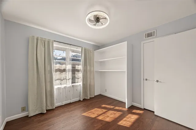 a view of an empty room with a window and wooden floor