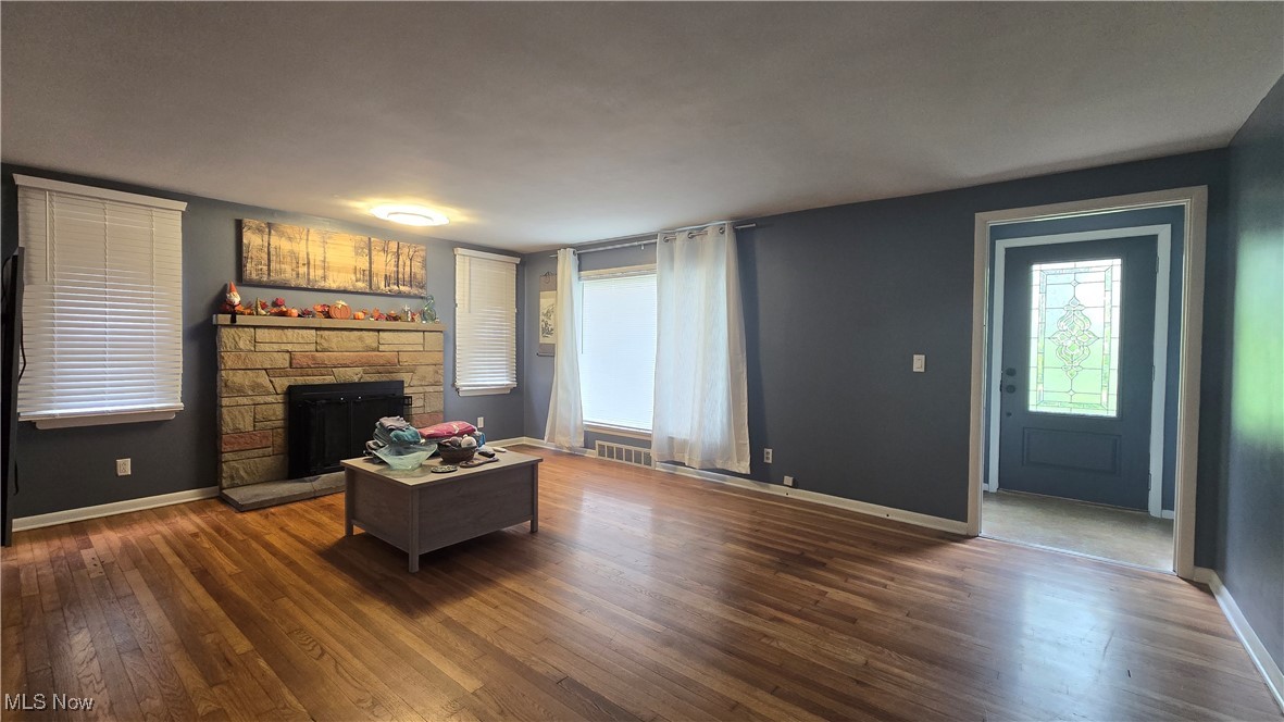 13232 Sperry Road Chesterland, OH 44026 - Photo 6 of 18 Living room featuring a stone fireplace, dark wood-style flooring, and baseboards