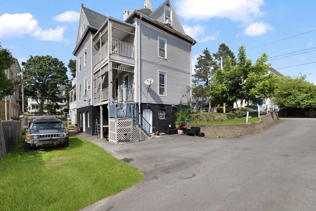 311 Elm Street Woonsocket, RI 02895 - Photo 26 of 29 a view of a building with a yard and a car parked in front of it