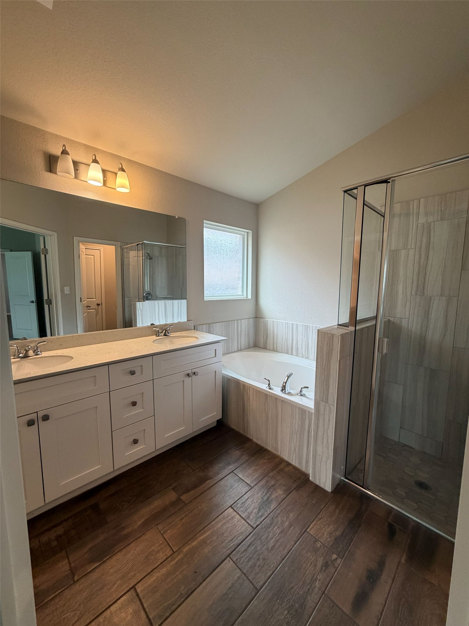 248 Falling Star Lane Georgetown, TX 78628 - Photo 11 of 16 An inviting primary bathroom featuring a double vanity, a deep soaking tub, and a glass-enclosed shower.