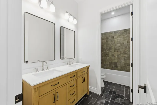 a bathroom with a double vanity sink mirror and shower