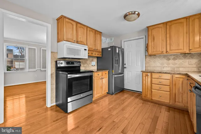 a kitchen with granite countertop wooden floors stainless steel appliances and sink