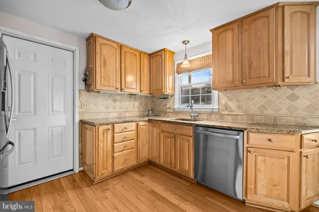 a kitchen with stainless steel appliances granite countertop wooden cabinets a sink and dishwasher with wooden floor