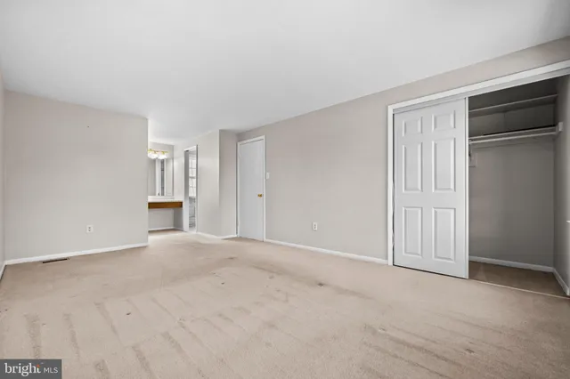 a view of an empty room with closet and entryway