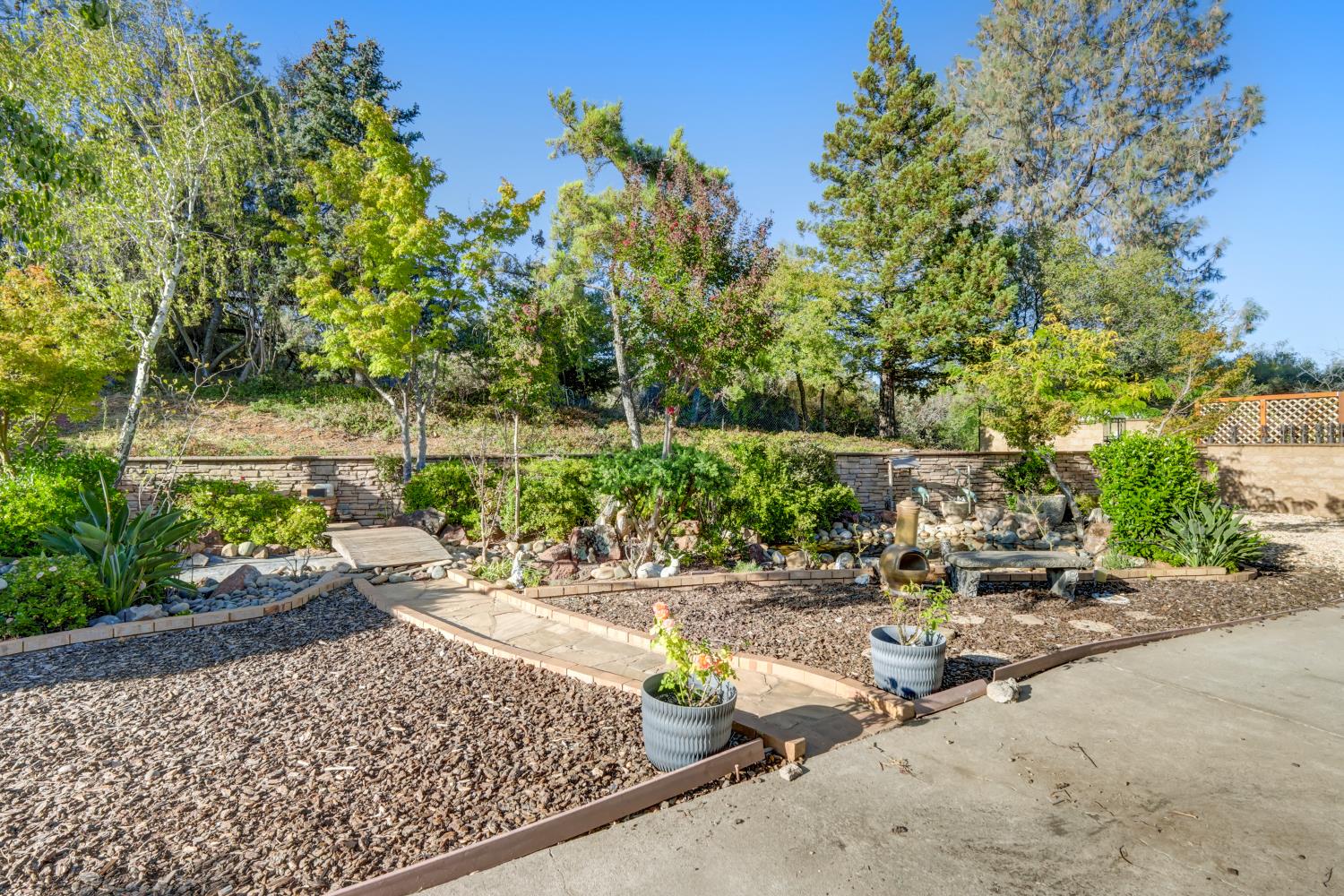2952 Royce Drive Rescue, CA 95672 - Photo 51 of 70 Landscaped outdoor area featuring a stone water feature, decorative stone retaining wall, and mature trees