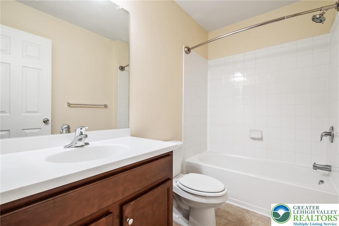 8455 Starling Road Breinigsville, PA 18031 - Photo 19 of 24 A pristine bathroom features a crisp white vanity and a bright tiled shower/tub combo.