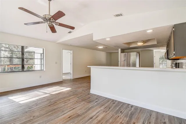 an empty room with ceiling fan and windows