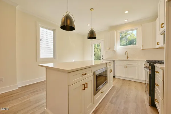 a kitchen with stainless steel appliances granite countertop a sink a window and wooden floor