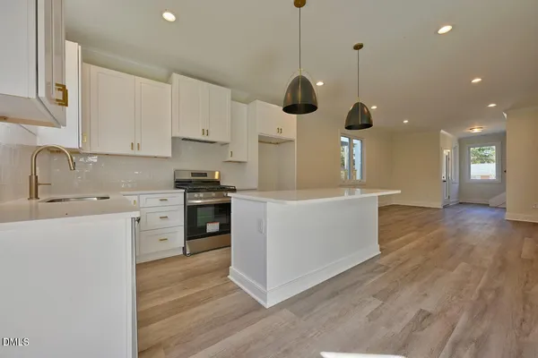 a kitchen with stainless steel appliances granite countertop a sink a stove and a wooden floors