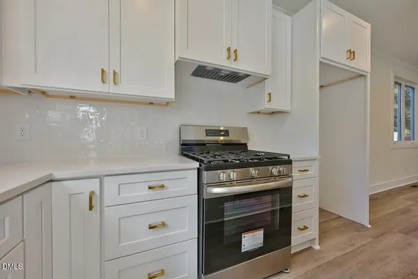 a kitchen with stainless steel appliances granite countertop white cabinets and a stove top oven