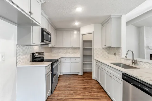 a kitchen with stainless steel appliances granite countertop a sink stove microwave and refrigerator