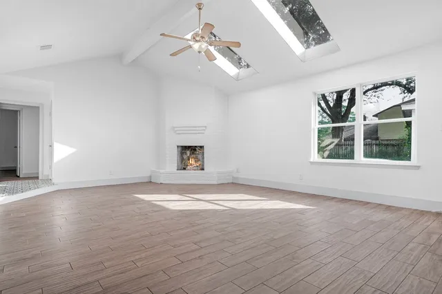 an empty room with wooden floor chandelier and windows