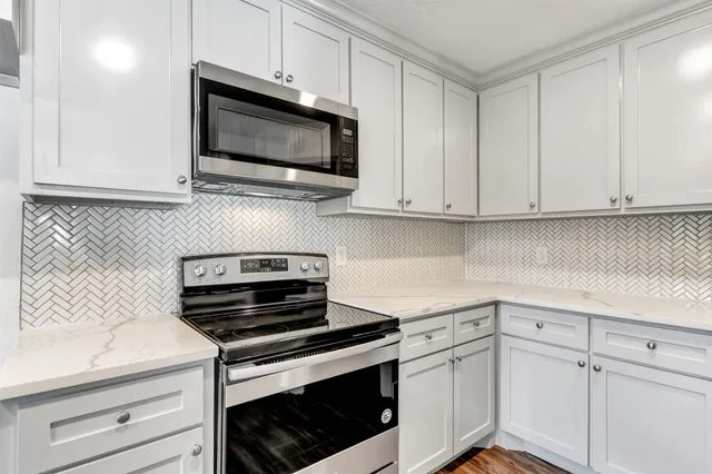 a kitchen with white cabinets and stainless steel appliances