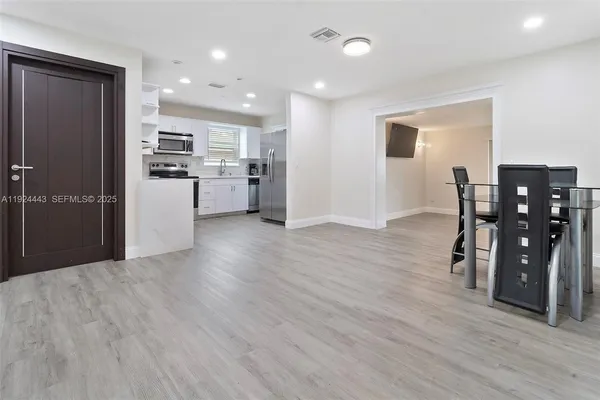 a kitchen with stainless steel appliances kitchen island granite countertop a refrigerator cabinets and wooden floor