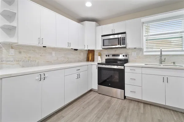 a kitchen with white cabinets stainless steel appliances and sink