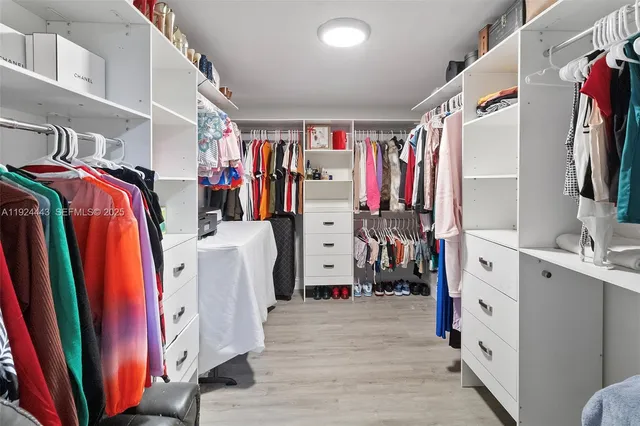 a view of walk in closet with clothes and shoes