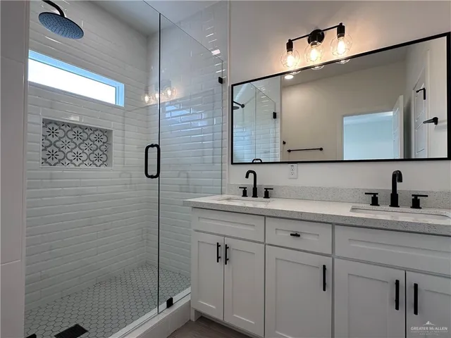 a bathroom with a double vanity sink a mirror and shower