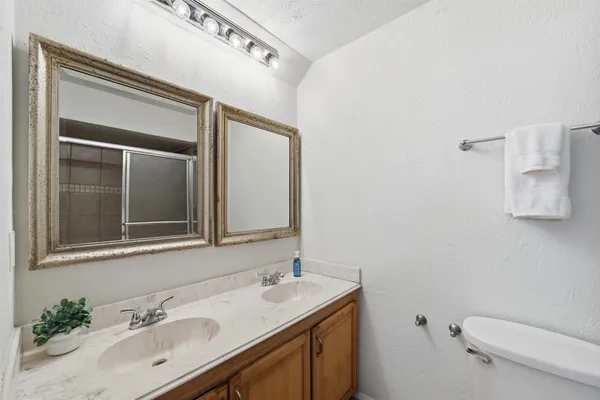 a bathroom with a granite countertop sink toilet and mirror