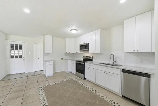 a kitchen with white cabinets appliances and sink