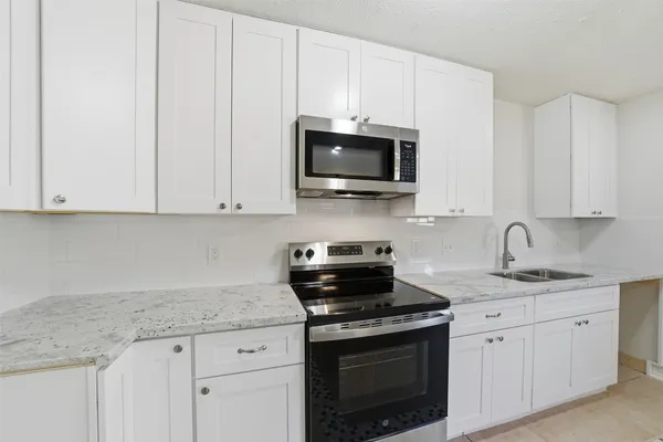 a kitchen with granite countertop white cabinets white stainless steel appliances and a sink