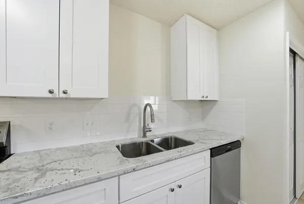 a kitchen with white cabinets a sink and dishwasher